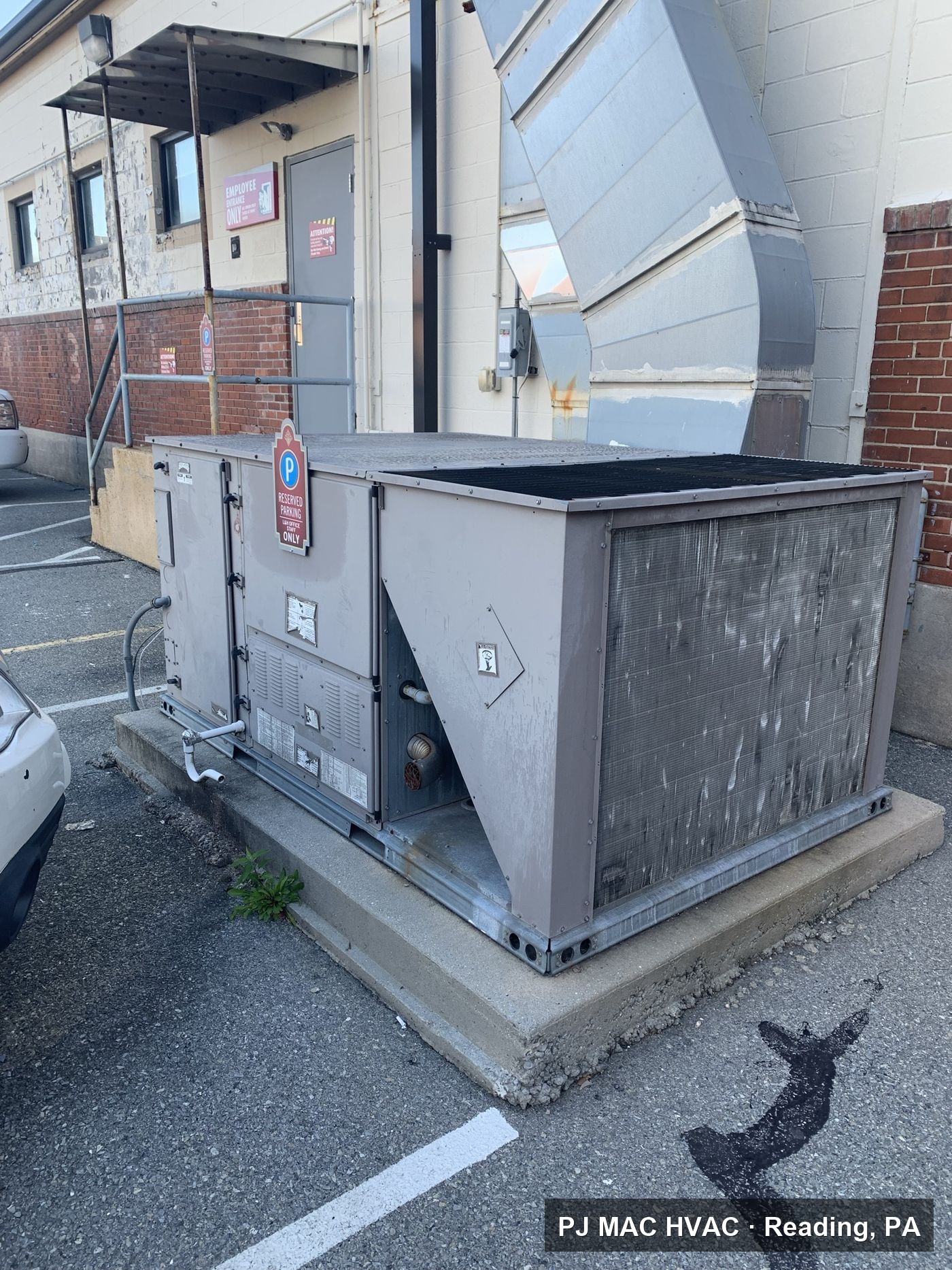 A commercial packaged HVAC unit on a concrete pad serviced by PJ MAC HVAC behind a Philadelphia-area business.