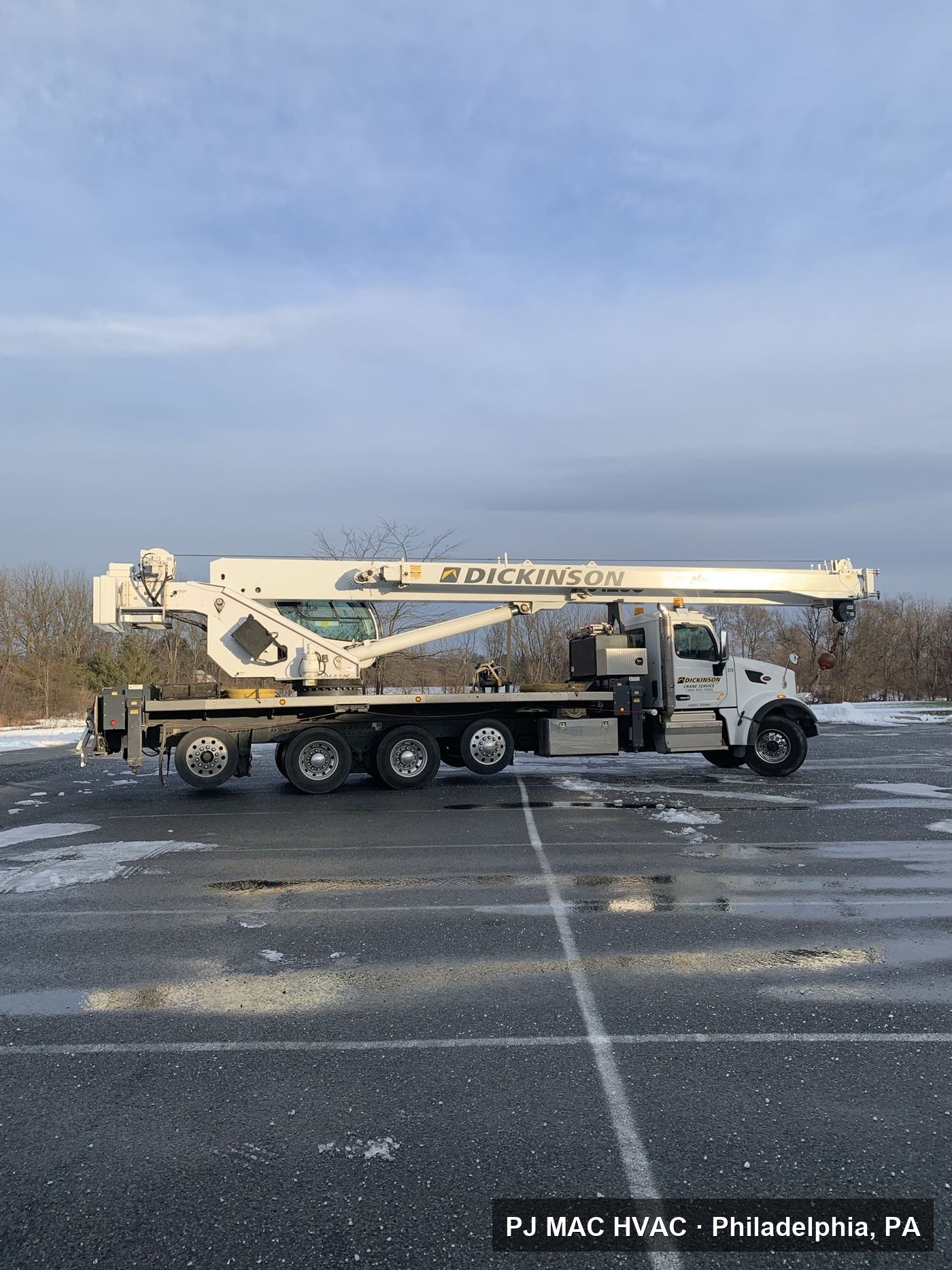 A boom crane truck staged for a PJ MAC HVAC rooftop equipment lift at a commercial site.