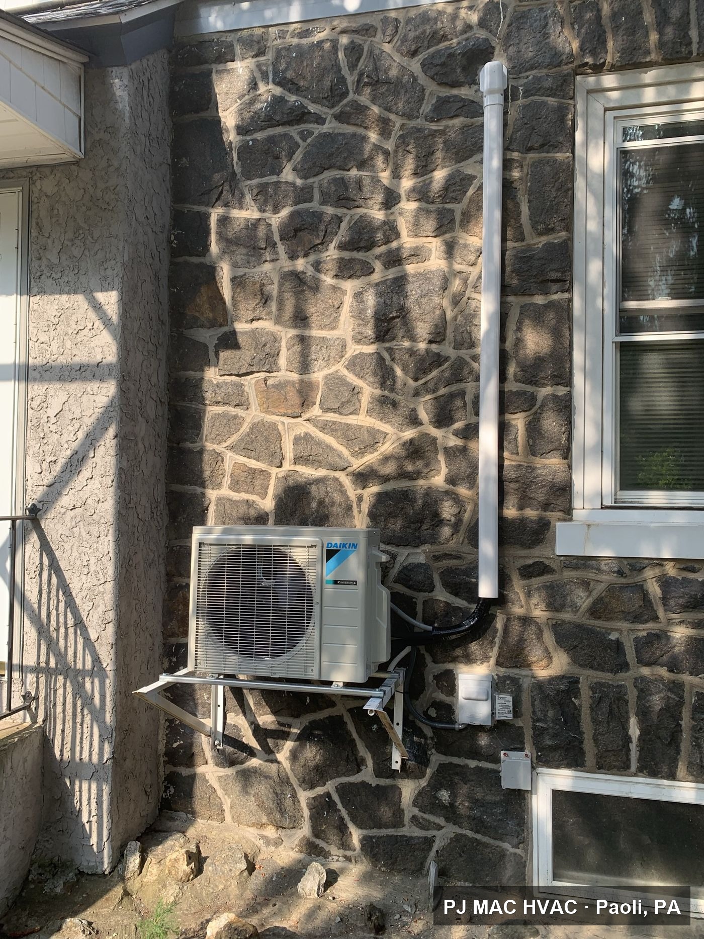 PJ MAC HVAC wall-mounted Daikin ductless mini-split condenser installed on the stone exterior of a Philadelphia-area home.