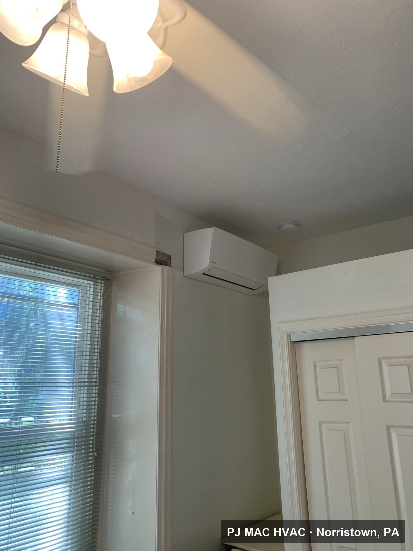 A ductless mini-split indoor unit installed by PJ MAC HVAC on a bedroom wall.