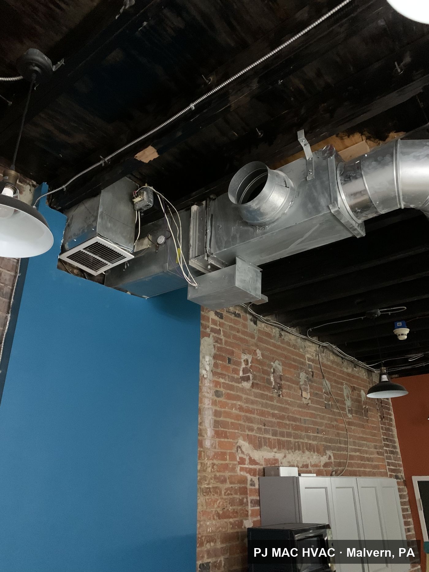 Exposed spiral ductwork installed by PJ MAC HVAC in a commercial space with brick walls.