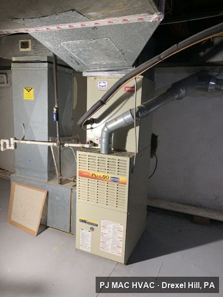 A gas furnace and flue venting installed by PJ MAC HVAC in a basement utility area.