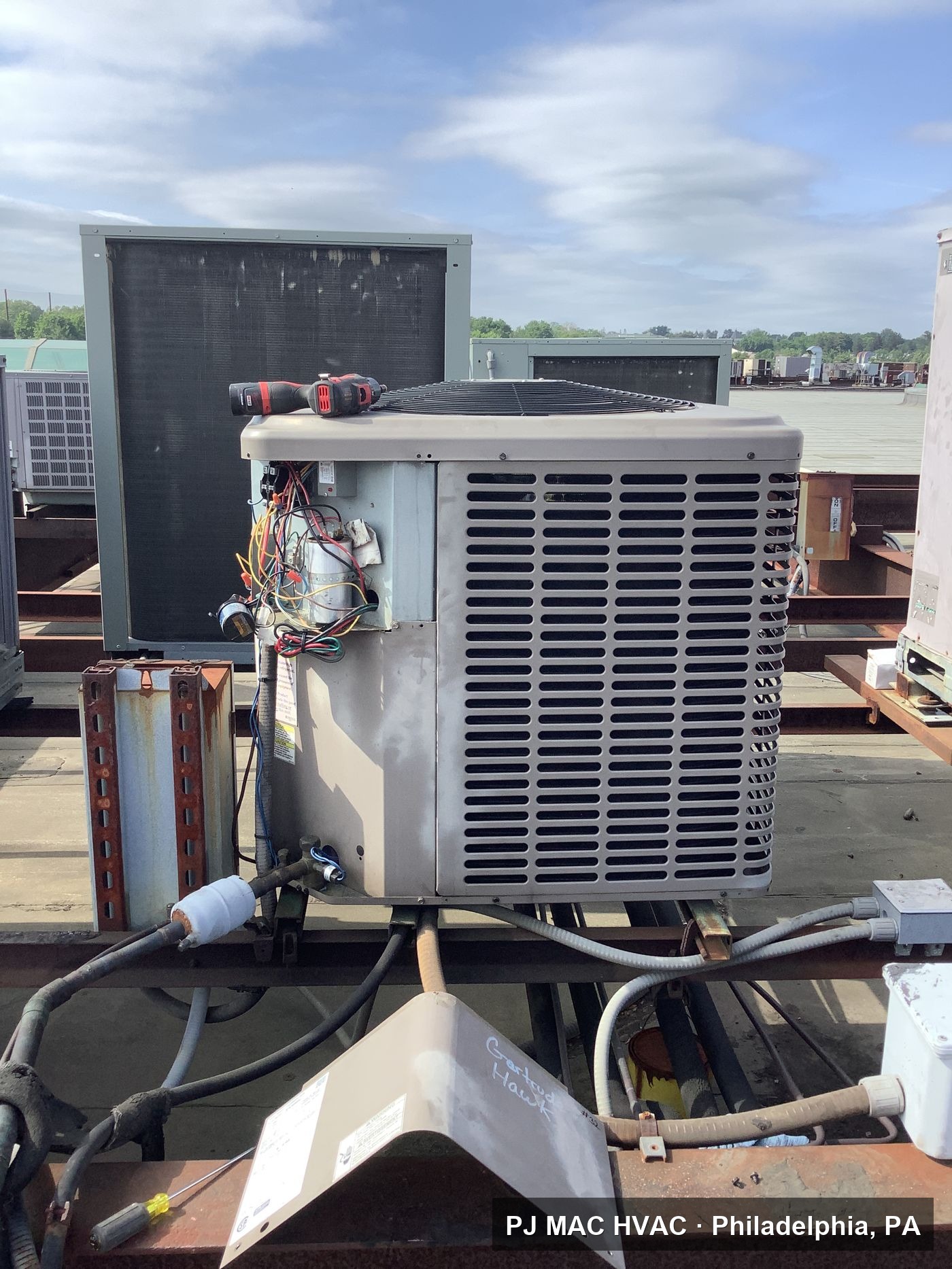 PJ MAC HVAC performs electrical repairs on a rooftop condensing unit at a commercial building.
