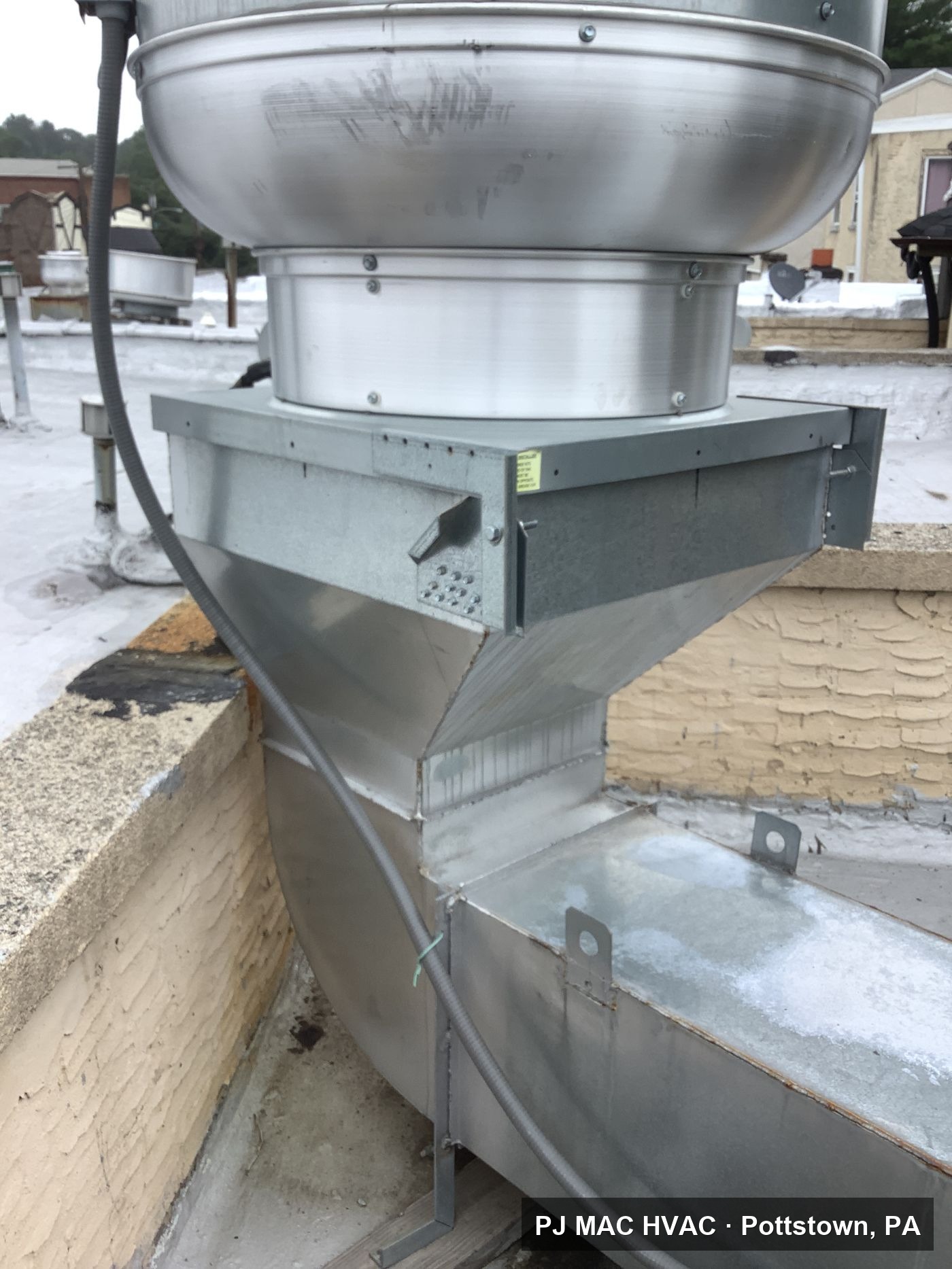 A rooftop exhaust fan installed by PJ MAC HVAC on a custom-fabricated sheet metal transition.