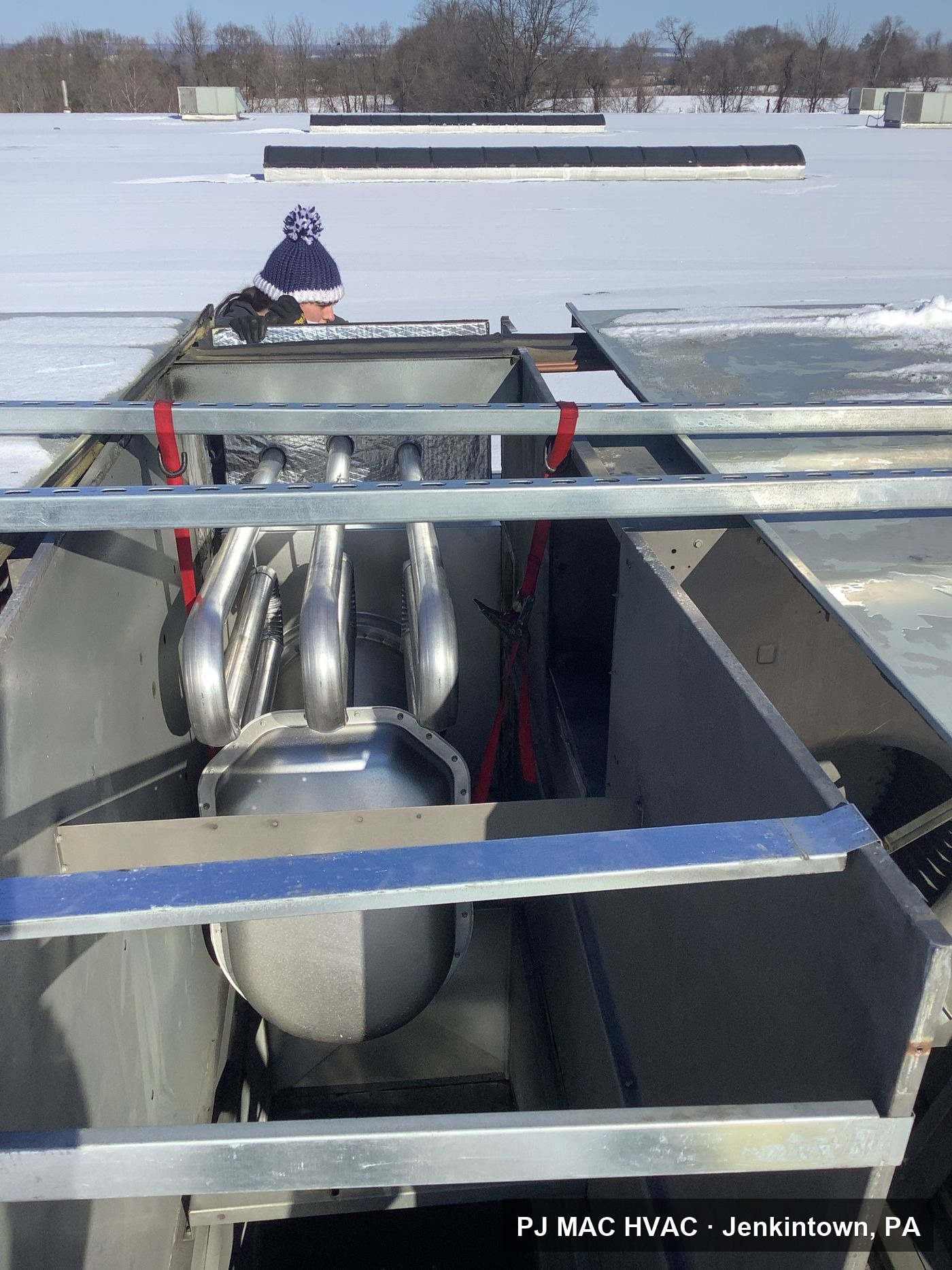 PJ MAC HVAC replaces the heat exchanger inside a commercial rooftop unit on a snowy day.