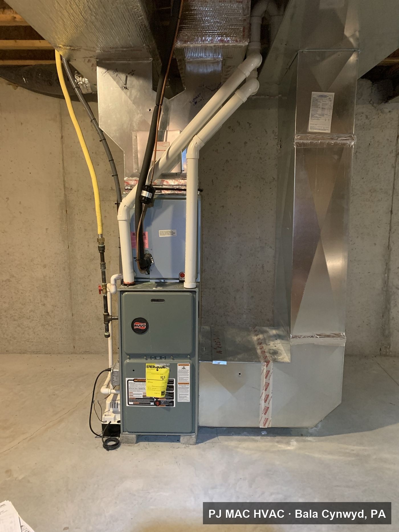 A new Ruud high-efficiency gas furnace with PVC venting installed by PJ MAC HVAC in a basement.